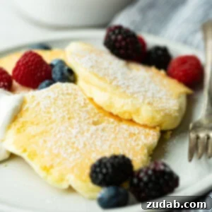 Pillowy Soft Japanese Pancakes 9 a photo of three fluffy Japanese cloud pancakes topped with powdered sugar and mixed fresh berries