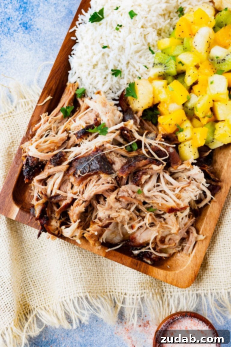 Weekly Meal Plan for October 23-29 4 A rectangular wooden platter overflowing with tender, juicy Kalua pulled pork, served alongside fluffy herbed rice, a vibrant tropical fruit salad, and golden Hawaiian rolls, showcasing a complete island-inspired meal.