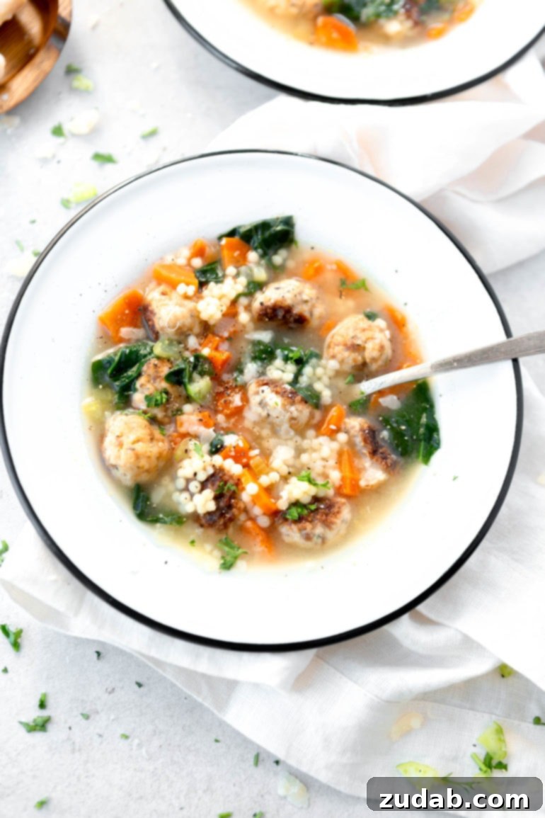 Weekly Meal Plan for October 23-29 5 A cozy bowl of Italian Wedding Soup, brimming with savory mini meatballs, tender pasta (like acini di pepe), vibrant carrots, and fresh spinach. A spoon rests invitingly in the soup, ready to be enjoyed.