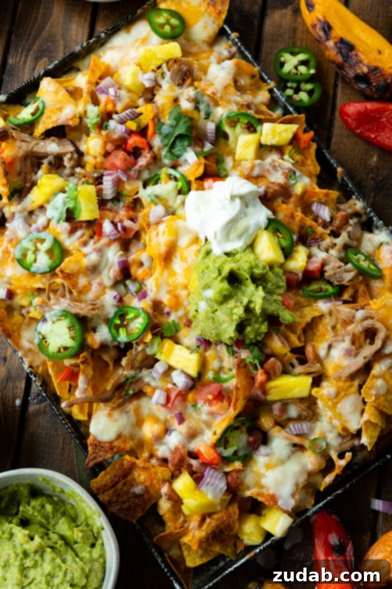 Weekly Meal Plan for October 23-29 6 An appetizing overhead shot of a sheet pan loaded with crispy tortilla chips, generously topped with savory pulled pork, melted cheese, and a colorful array of fresh nacho toppings, all drizzled with a unique and creamy pina colada sauce.