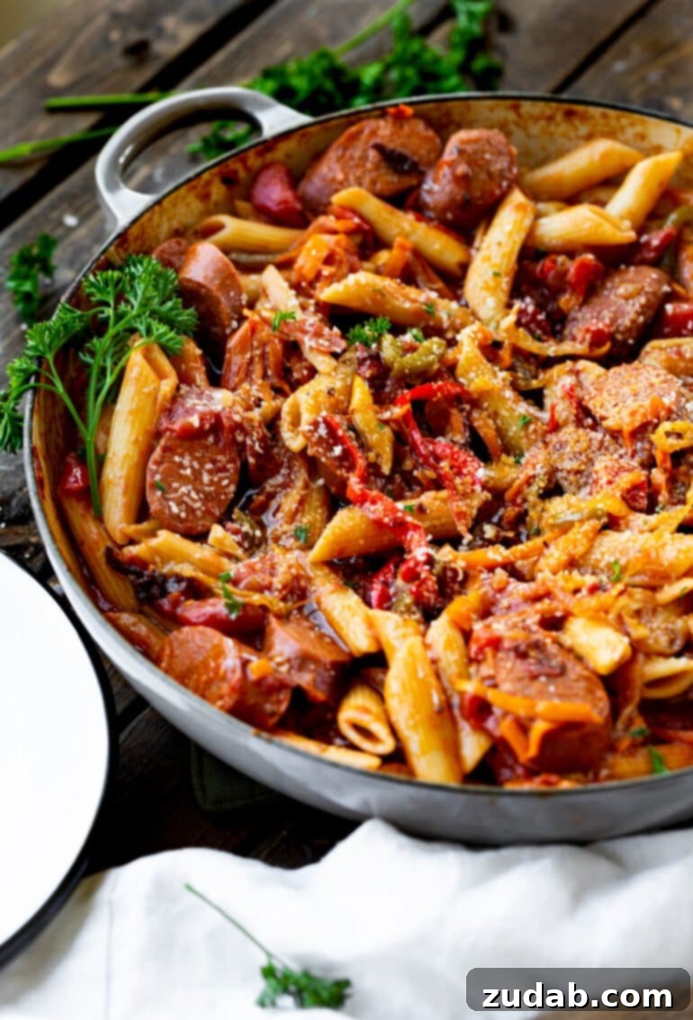 Weekly Meal Plan October 30 to November 5 3 A close-up photo of a cast iron skillet brimming with savory Italian sausage, colorful bell peppers, and tender onions, perfectly mixed with cooked penne pasta.
