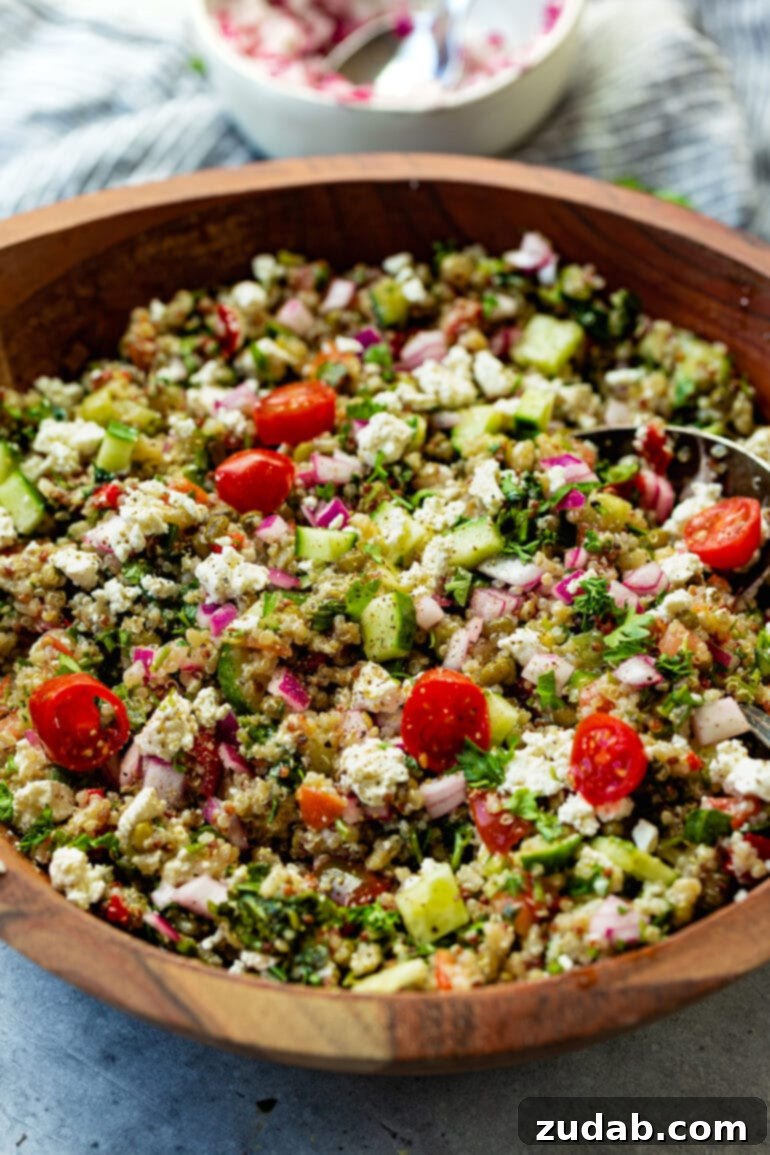 Weekly Meal Plan October 30 to November 5 6 A large wooden serving bowl filled with a fresh and colorful Mediterranean quinoa salad, featuring tomatoes, cucumbers, red onions, and an abundance of fresh herbs.