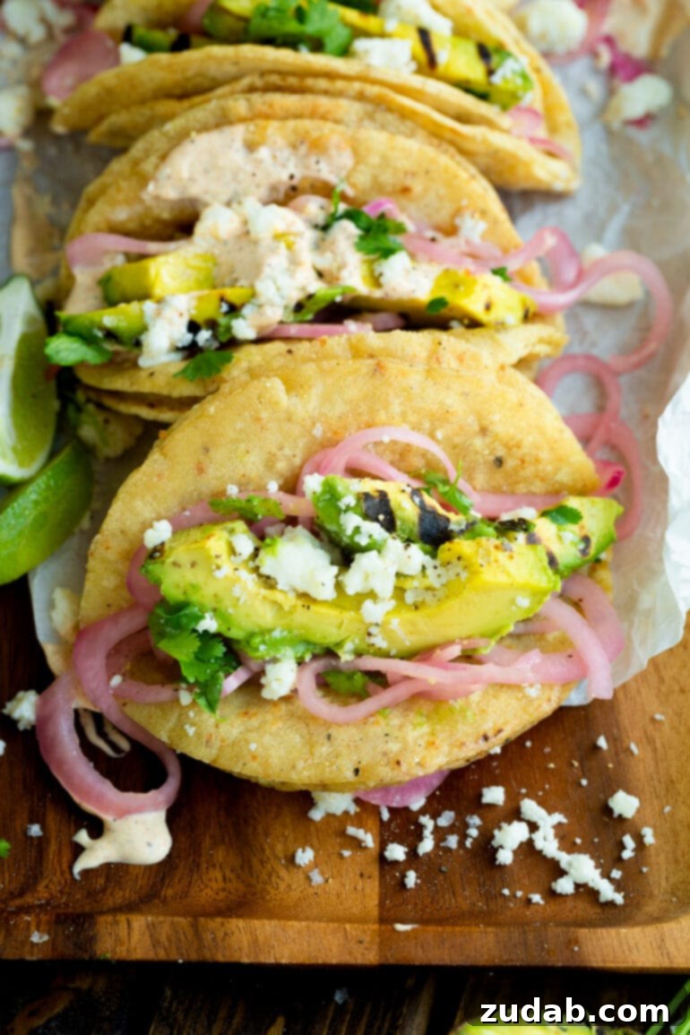 An overhead photo of a taco generously filled with slices of grilled avocado, vibrant pickled red onions, crumbly queso fresco, and seasoned with a touch of salt and pepper.