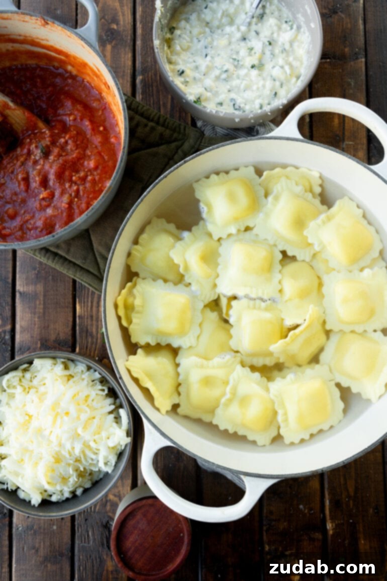 Effortless Skillet Ravioli Lasagna 4 A visual feast of skillet lasagna ingredients, neatly arranged in separate bowls: perfectly cooked raviolis, a rich red meat sauce, finely shredded Parmesan, and a creamy cottage cheese layer.