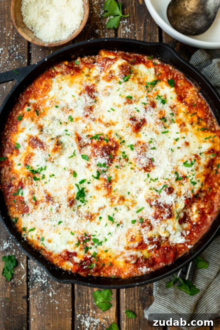 Effortless Skillet Ravioli Lasagna 5 A tantalizing photo of a bubbling cast iron skillet filled to the brim with lazy lasagna, generously topped with melted mozzarella cheese and a scattering of fresh chopped parsley.