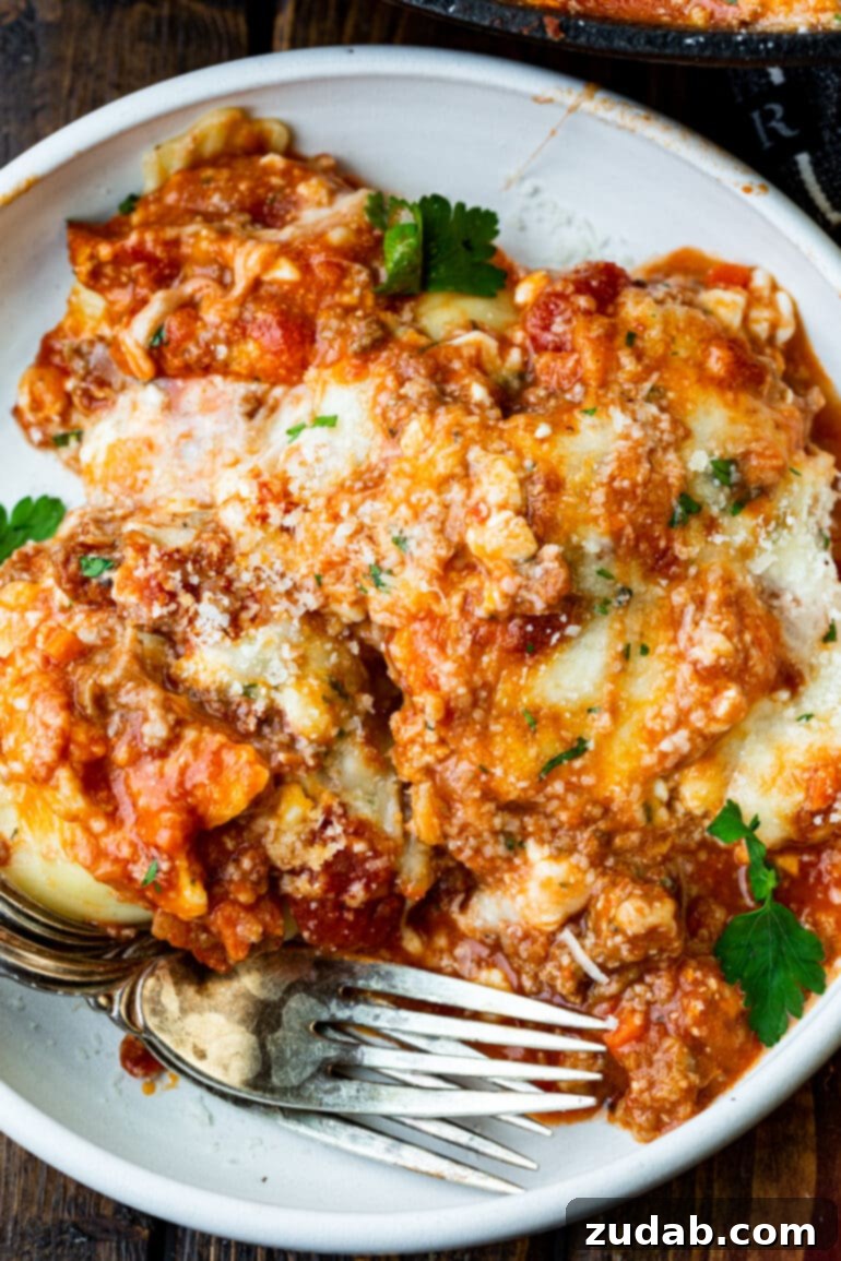 Effortless Skillet Ravioli Lasagna 6 A stunning close-up photo of a generous serving of lazy ravioli skillet lasagna, perfectly plated on a white dinner plate, ready to be devoured.