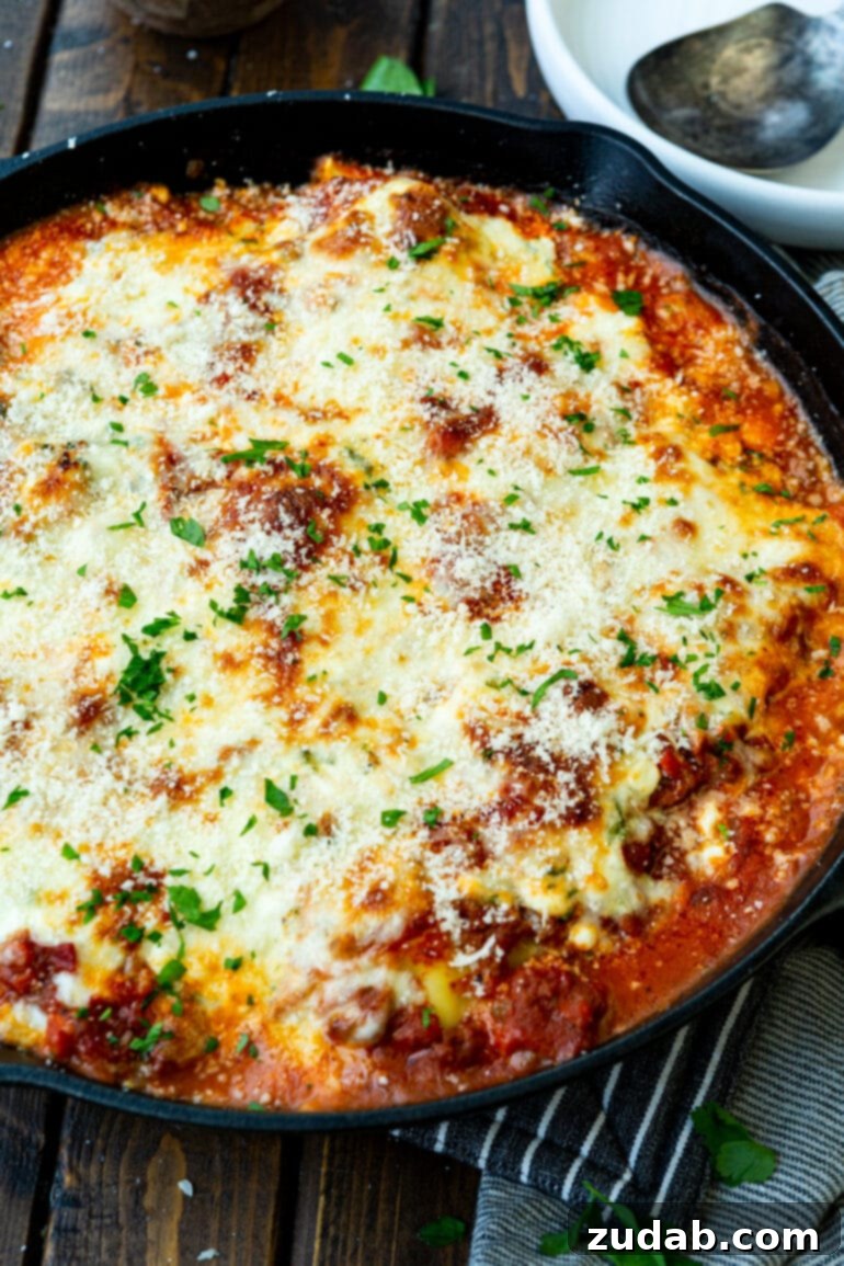 Effortless Skillet Ravioli Lasagna 7 An appetizing overhead shot of a cast iron skillet brimming with ravioli lazy lasagna, featuring a top layer of perfectly melted mozzarella cheese and a garnish of vibrant chopped parsley.