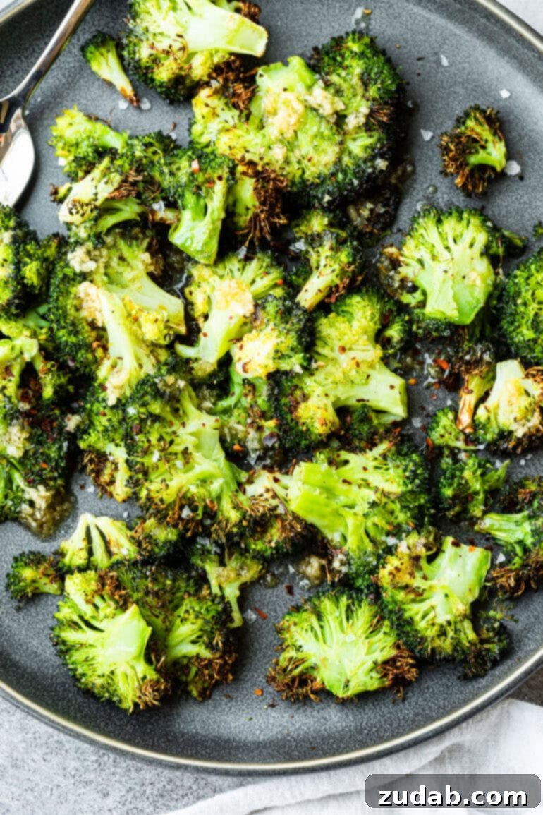Golden Crispy Air Fryer Smashed Broccoli 3 A close-up shot of a plate brimming with perfectly smashed air fryer crispy broccoli florets, ready to be enjoyed. Highlighted are their vibrant green color and crunchy, golden edges, embodying a quick and healthy vegetable side.
