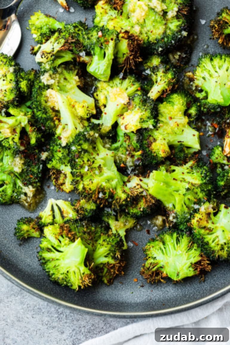 Golden Crispy Air Fryer Smashed Broccoli 5 A high-angle shot of crispy broccoli florets beautifully piled on a large gray plate, emphasizing their golden-brown char. A perfect visual for an easy, delicious air fryer broccoli recipe ready in minutes.