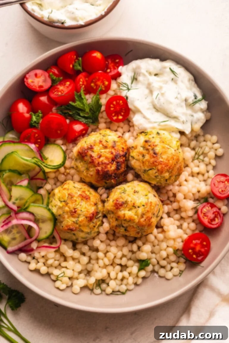 Herb-Infused Greek Chicken Meatballs 2 Greek Chicken Meatballs served with couscous, tzatziki, and tomatoes