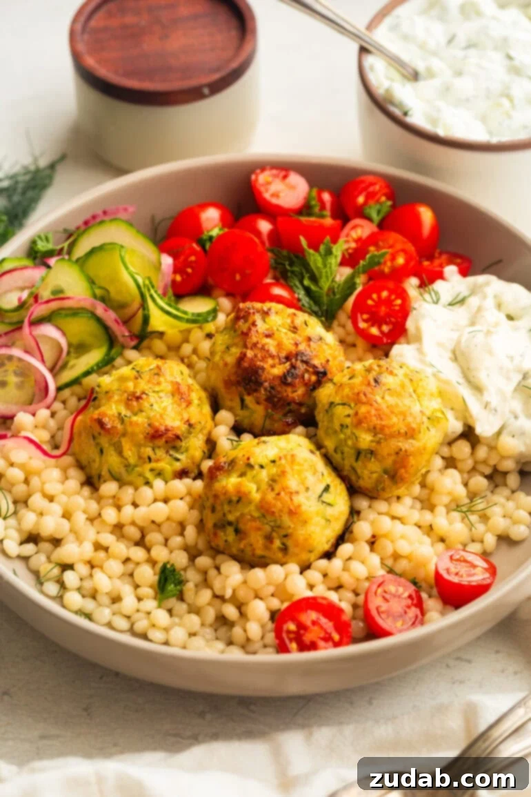 Herb-Infused Greek Chicken Meatballs 5 Greek Chicken Meatballs with couscous, tzatziki, cucumber salad, and tomatoes