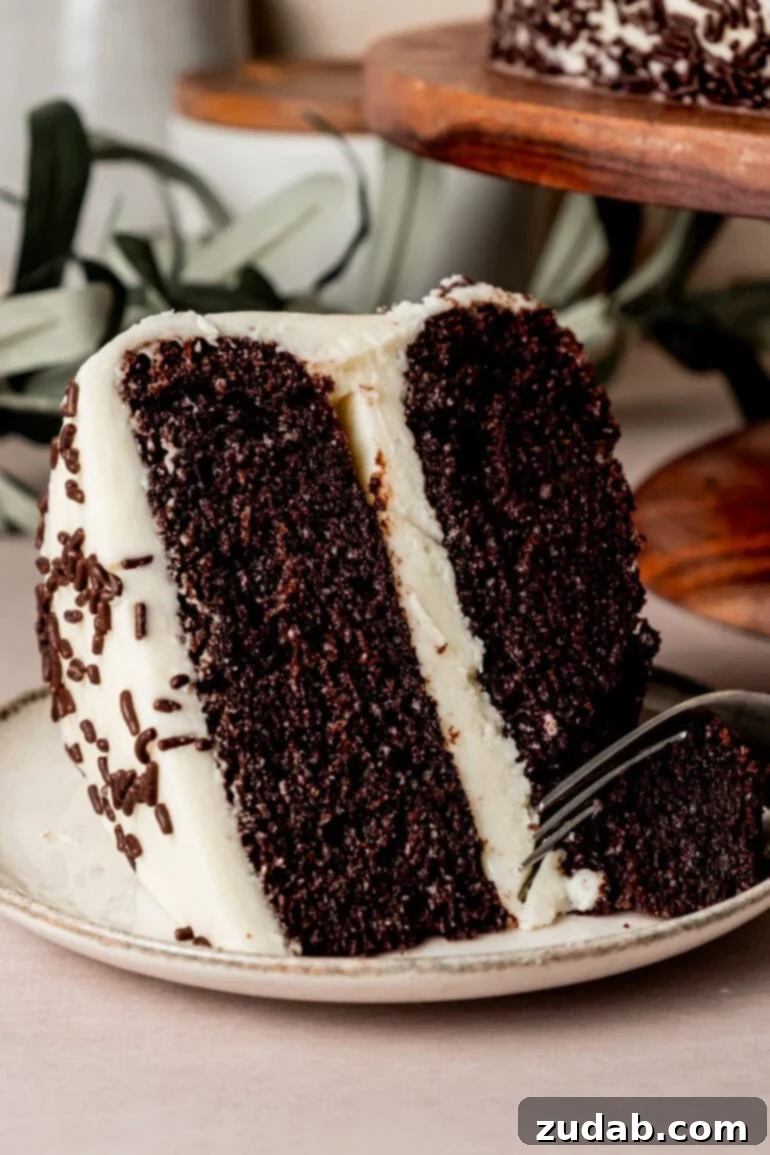From Box to Bliss: Elevating Simple Chocolate Cake 22 A slice of two-layer chocolate cake with vanilla buttercream frosting and chocolate sprinkles, with a fork removing a bite from it.