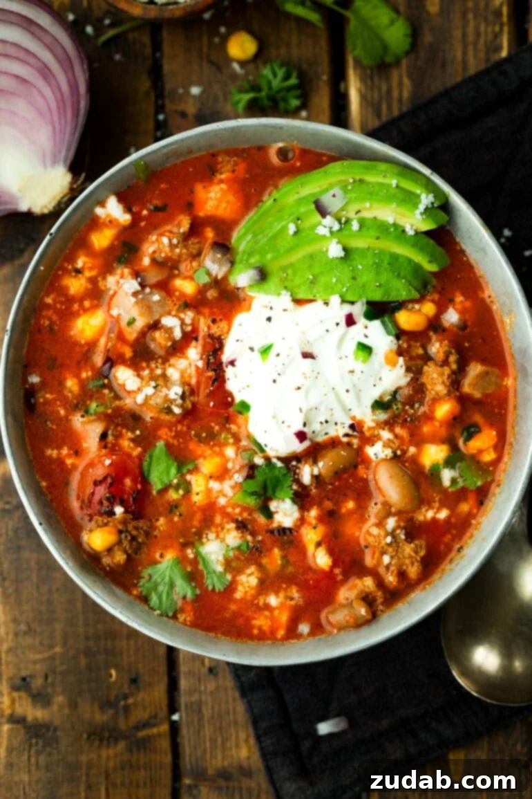 Cowboy Pinto Bean Soup Recipe 4 A bowl of charro bean soup with pinto beans, corn, chorizo, bacon, and toppings