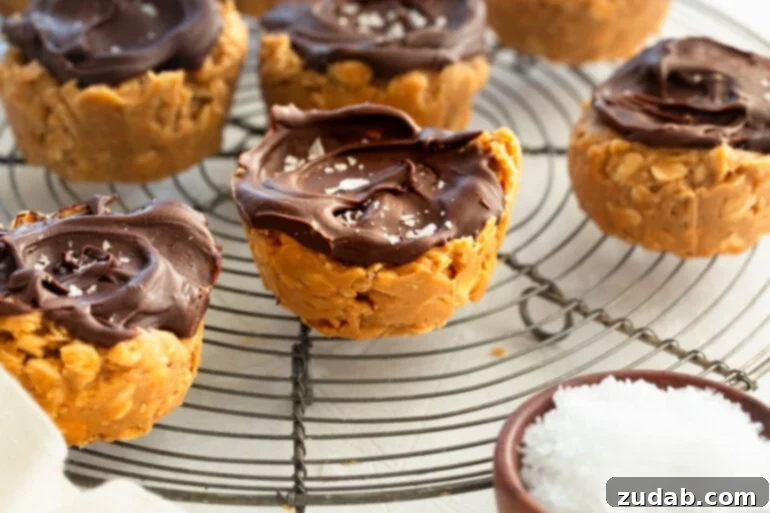Chocolate Peanut Butter Oatmeal Cups 5 Several peanut butter oat cups topped with chocolate and flaked sea salt sitting on a wire cooling rack