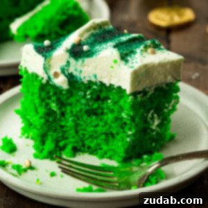 a piece of green lime jello cake topped with white frosting and sprinkled with green sprinkles sitting on a small dessert plate