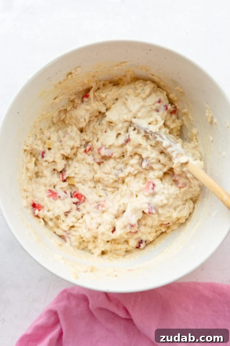 Super Soft Strawberry Oat Muffins Infused with Greek Yogurt 6 A mixing bowl filled with the luscious, thick batter for healthy berry breakfast cake, showcasing bits of oats and diced strawberries.