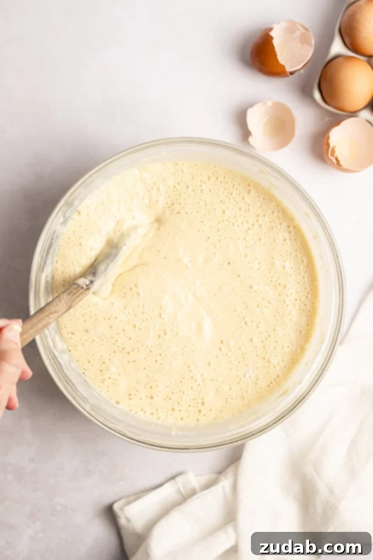 Step-by-step image of folding in melted butter into the pancake batter.