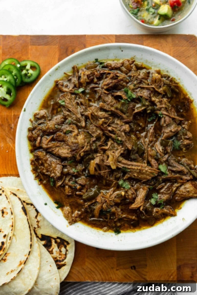 Fall-Apart Poblano Beef Tacos from One Pot 6 Close-up of juicy Mexican shredded meat alongside sliced jalapeños, and tortillas