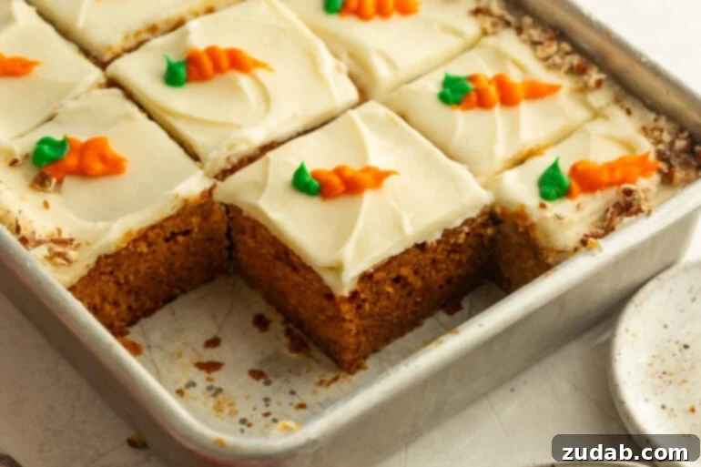 Effortless Carrot Cake: The Baby Food Secret 3 a baking pan with carrot cake slices in it topped with cream cheese frosting with a little carrot piped on each piece