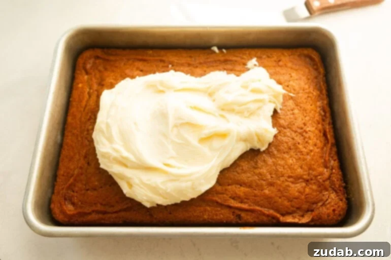 Effortless Carrot Cake: The Baby Food Secret 7 a baked carrot cake in a a 9x13 baking pan with cream cheese frosting piled on top ready to be spread out