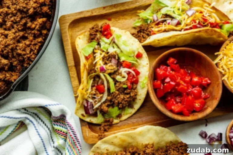 Speedy Weeknight Beef Tacos 2 a wooden board topped with ground beef tacos in corn tortillas