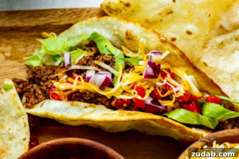Speedy Weeknight Beef Tacos 7 a ground beef taco topped with cheddar cheese, shredded lettuce, diced red onions and tomatoes