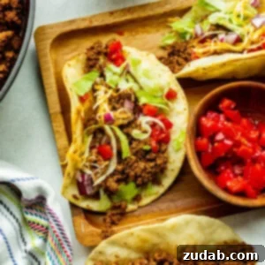 Speedy Weeknight Beef Tacos 8 a wooden board topped with ground beef tacos in corn tortillas