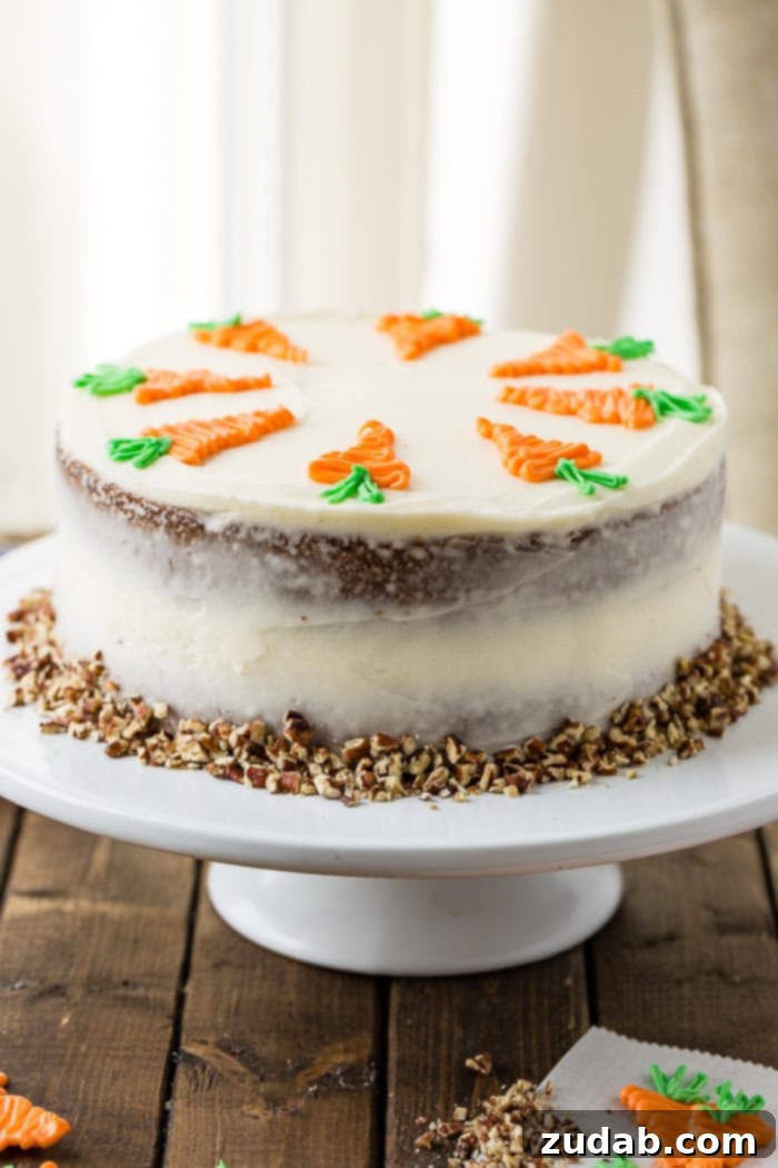 Ultimate Moist Carrot Cake with Cream Cheese Frosting 7 A two-layer carrot cake on a white cake stand, richly covered in white cream cheese frosting and topped with white chocolate decorative carrots, with chopped walnuts scattered at its base.