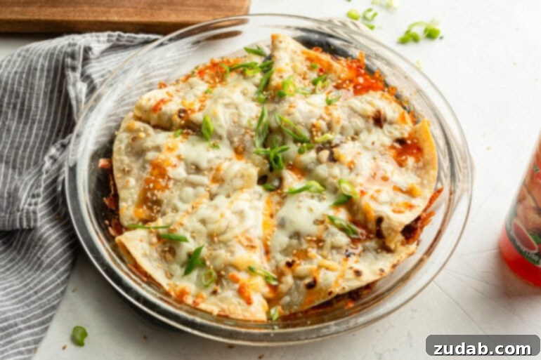 Crispy Korean Beef Pockets Speedy Weeknight Delight 6 a photo of a pie dish filled with crispy tortilla korean beef pockets topped with melted cheese, sweet chili sauce and diced green onions
