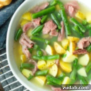 a photo of a bowl of ham hock soup loaded with potatoes, green beans and chunks of ham