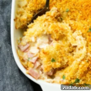 a photo of a chicken cordon bleu casserole with a serving being removed