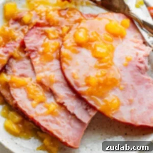 A photo of a spiral cut ham sitting on a serving platter topped with a juicy pineapple glaze, perfect for a slow cooker ham recipe.