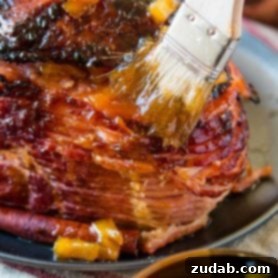 Brushing sauce on a World's Best Brown Sugar Ham, highlighting its rich, sweet glaze.
