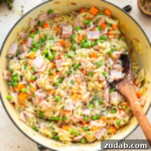 Lemon Orzo with ham, peas, carrots and parmesan cheese in a skillet.