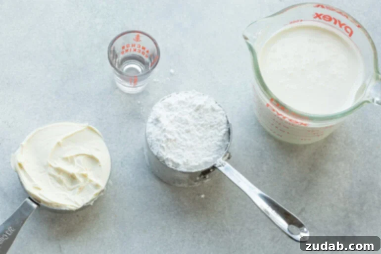 Luxurious Mascarpone Whipped Cream 3 A beautifully arranged overhead shot of all the essential ingredients for mascarpone whipped cream, neatly separated in their containers: a carton of heavy cream, a bowl of powdered sugar, a bottle of clear vanilla extract, and a tub of creamy mascarpone cheese.