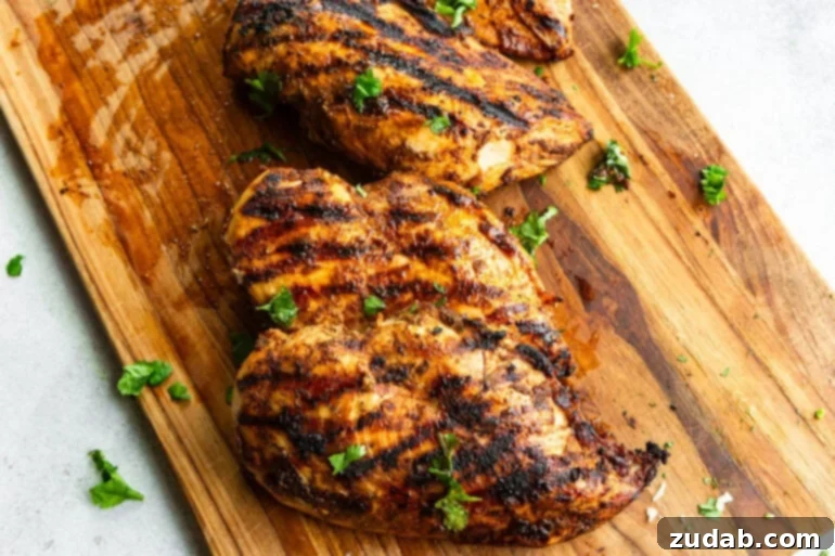 Zesty Mexican Grilled Chicken 3 A photo of smoky taco seasoned grilled meat resting on a cutting board with beautiful char marks on both sides.