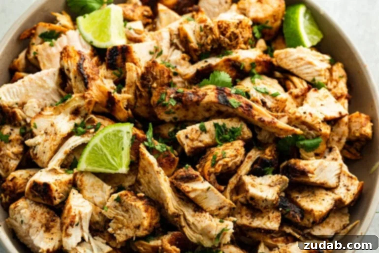 Zesty Mexican Grilled Chicken 6 A close up photo of juicy Mexican Grilled Chicken shredded in a beige bowl with a squeeze of fresh lime juice on top.