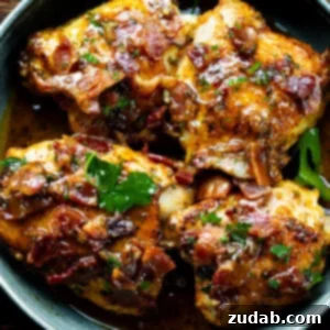 A skillet with four golden chicken thighs topped with crispy bacon and chopped parsley.