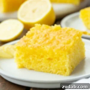 a photo of a piece of moist lemon jello cake sitting on a small white dessert plate