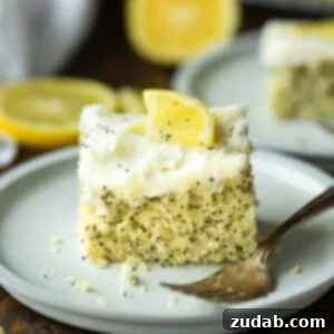 a photo of a piece of lemon poppy seed cake topped with a white cream cheese frosting and small lemon slice