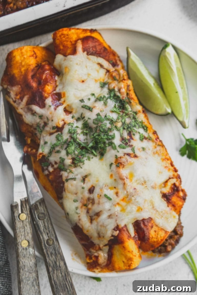Easy Authentic Cinco de Mayo Recipes for Your Fiesta 16 Two enchiladas on a dinner plate with lime wedges and silverware. The enchiladas are covered with melted cheese and chopped cilantro.