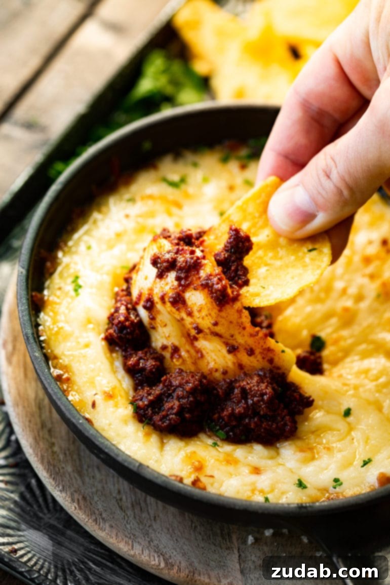 Easy Authentic Cinco de Mayo Recipes for Your Fiesta 36 a photo of someone using a tortilla chip to scoop up a big bite of chorizo queso fundido.