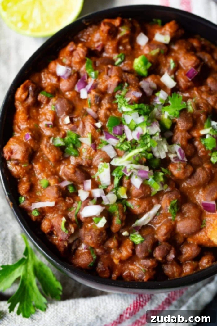 Easy Authentic Cinco de Mayo Recipes for Your Fiesta 48 A photo of a bowl of Mexican black beans stopped with diced red onion and chopped fresh cilantro.