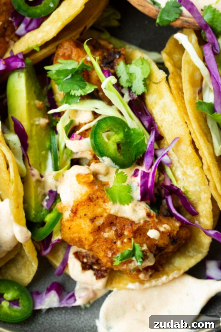 Easy Authentic Cinco de Mayo Recipes for Your Fiesta 6 a photo of a fish taco with golden tender fish topped with shredded cabbage, slice jalapenos, chopped cilantro a creamy taco sauce.