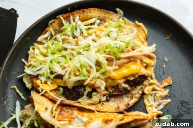 Smash Burger Taco Sensation 8 An open smash burger taco revealing the melted cheese, shredded iceberg lettuce, and creamy burger sauce inside a crispy tortilla.