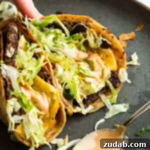 A hand picking up a smash burger taco