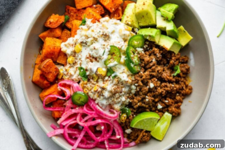 Street Corn Ground Beef Sweet Potato Power Bowl 6 A close-up of a high-protein Mexican street corn sweet potato bowl with ground beef, generous avocado slices, tangy pickled red onions, and a fresh lime wedge, ready to be enjoyed.