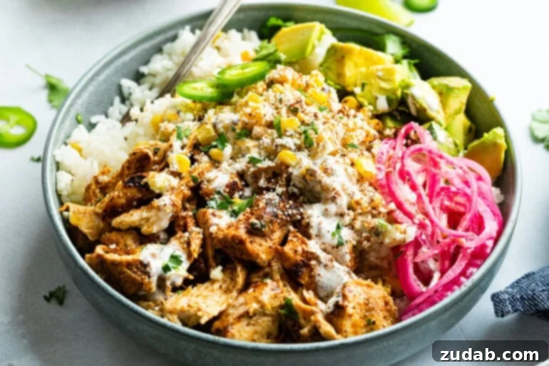 Creamy Esquites Chicken Rice Bowls 2 A Mexican chicken rice bowl topped with creamy elote, pickled red onions, avocado, and jalapeño slices, showcasing vibrant colors and fresh ingredients.