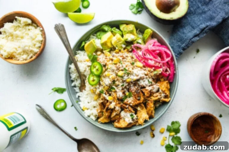 Creamy Esquites Chicken Rice Bowls 3 An overhead shot of a Mexican chicken and rice bowl with street corn, pickled red onions, avocado, and jalapeños, highlighting the colorful and fresh ingredients.