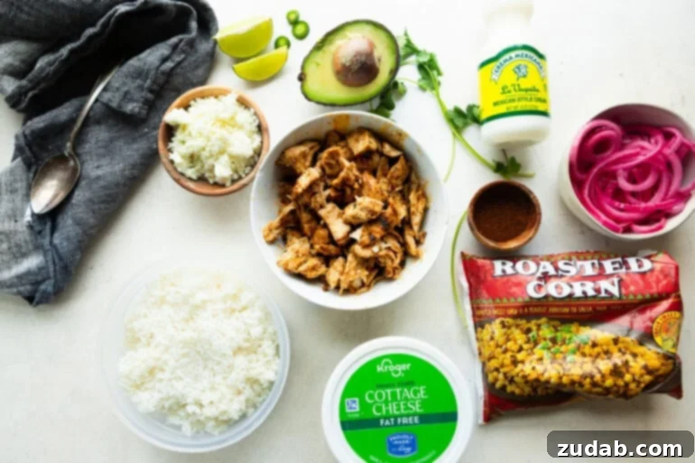 Creamy Esquites Chicken Rice Bowls 4 All the ingredients for street corn chicken rice bowls laid out, including seasoned chicken chunks, cottage cheese, roasted corn, avocado, rice, Mexican crema, and various seasonings.